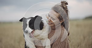 Dog lover stylish girl wearing sunglasses hugging her doggy during they walk. Portrait of smiling young woman kissing