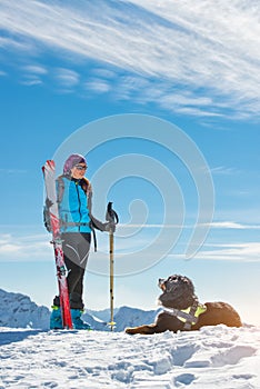 Dog in the mountains in the snow with mistress in alpine skiing