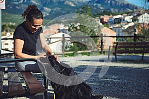 The dog is my best companion. Woman sitting on a bench in the mountains, stroking her dog, smiling enjoying a happy time
