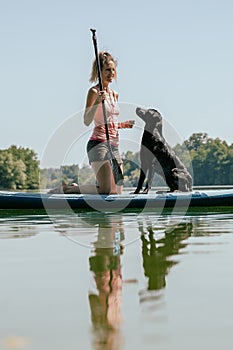 Dog owner and her black labrador retriever on a sup board