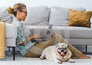 Dog owner lover lifestyle concept. Cute woman using laptop computer sitting on the floor with best friend dog looking on camera