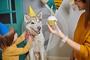 Dog pet birthday party, Happy family mother and child congratulating pet with birthday cupcake, child hugging a dog