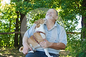 Dog is ready for to lick bearded Caucasian man while sittimg on the master hands