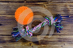 Dog rope toy with tied knots and toy ball on a wooden background. Top view