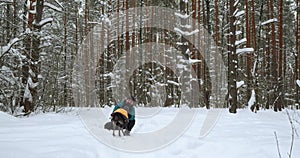 The dog runs into the arms of his master while walking through the winter forest