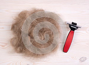 Dog`s hair and a pet comb with scissors on a wooden background after trimming a dog