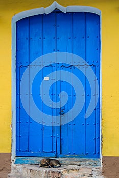 Dog sleeping in front of blue door in Trinidad, Cuba
