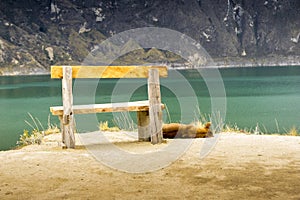 Dog sleeping near wooden chair in front of Quilotoa lake photo