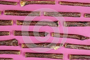 Dog treat sticks on a pink background. Dried beef esophagus.