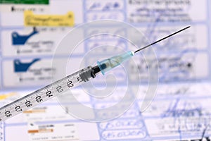 Dog vaccination concept with syringe injection on blurry European pet passport in background