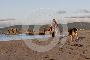 dog and woman walking on the beach sand