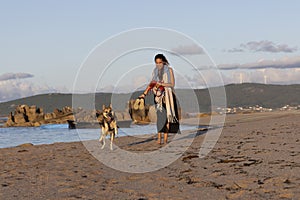 dog and woman walking on the beach sand