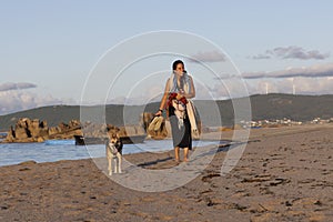 dog and woman walking on the beach sand