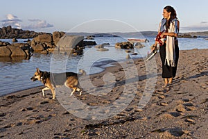 dog and woman walking on the beach sand