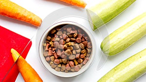 Dogfood, carrot and courgette on table background top view