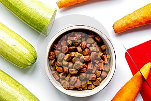 Dogfood, carrot and courgette on table background top view