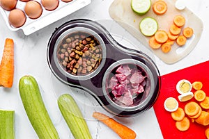 Dogfood, eggs, meat, carrot and courgette on table background top view