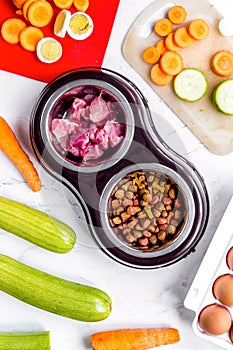 Dogfood, eggs, meat, carrot and courgette on table background top view photo