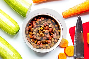 Dogfood set with cut vegetables and knife on table background to