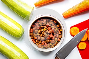 Dogfood set with cut vegetables and knife on table background to