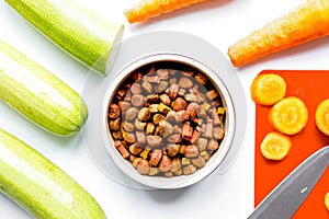 Dogfood set with cut vegetables and knife on table background to