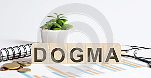 DOGMA word on the wood blocks concept with chart, coins, notebook and glasses