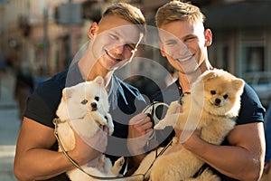Dogs bring them joy. Muscular men with dog pets. Happy twins with muscular look. Spitz dogs love the company of their
