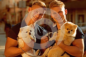 Dogs bring them joy. Muscular men with dog pets. Happy twins with muscular look. Spitz dogs love the company of their