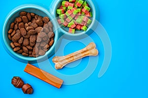 Dogs food in bowl and snacks on blue background top view