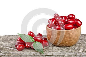 Dogwood berry with leaf in bowl on wooden table with white background