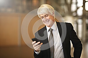 Doing business the modern way. a senior businessman using his cellphone in the office.