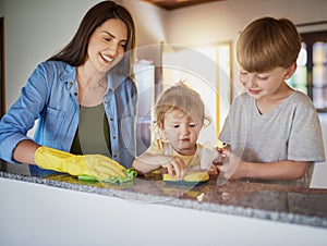 Doing chores is a great way to teach kids about responsibility. Shot of a mother and her two little children doing