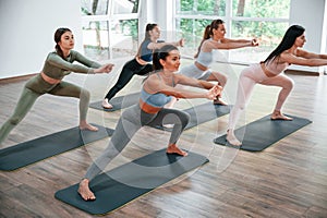 Doing exercises on the mats. Group of women practicing fitness in the gym