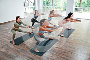 Doing exercises on the mats. Group of women practicing fitness in the gym