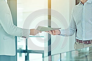 Doing a handover. Shot of a businessman handing a document to a colleague.