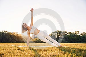 Doing hands practive. Beautiful woman in sportive clothes doing fitness exercises outdoors on the field