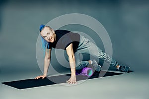 He doing leg exercise by dint of roller for myofascial relaxation on a gray