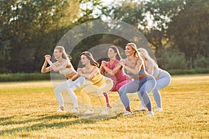 Doing legs exercises. Group of women have fitness outdoors on the field together