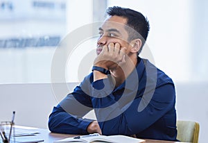 Doing nothing but hoping everything gets done... a young businessman looking bored while working in an office.