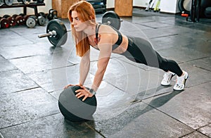 Doing push ups by using soft ball. Beautiful strong woman is in the gym