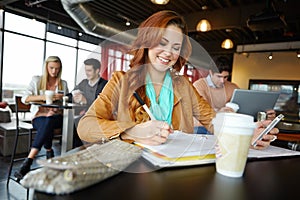 Doing some studying on the go. A beautiful young university student using her smartphone in a coffeee shop while