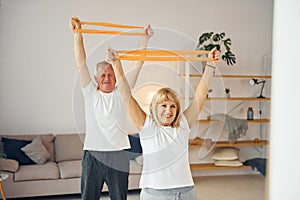 Doing stretching and fitness exercises. Senior man and woman is together at home