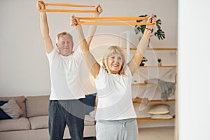 Doing stretching and fitness exercises. Senior man and woman is together at home