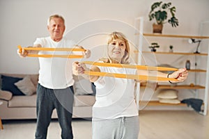 Doing stretching and fitness exercises. Senior man and woman is together at home