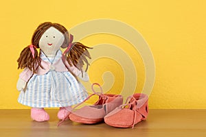 Doll and bootees for baby room interior on wooden table