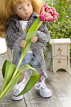 Doll in casual outfit with tulip
