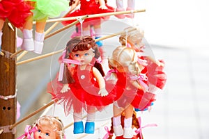 Doll in colorful dresses hanging on wooden stick for sell