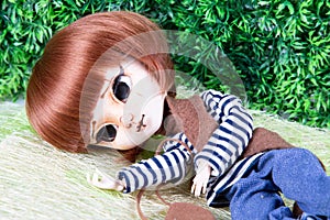 Doll face lying beautiful redhead puppet in green background