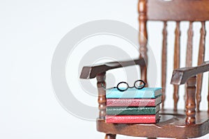 Doll house interior - a pile of books and glasses on the armchair isolated against white background