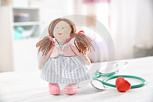 Doll, stethoscope and heart on table indoors.